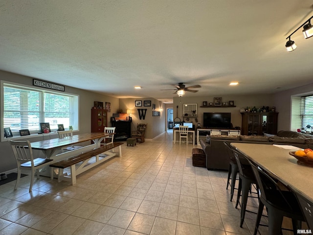 tiled dining area with a textured ceiling, rail lighting, and ceiling fan