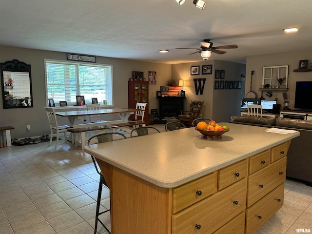 kitchen featuring light tile patterned flooring, ceiling fan, a kitchen breakfast bar, and a kitchen island