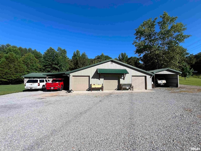 view of front of property with a garage, a carport, and an outdoor structure