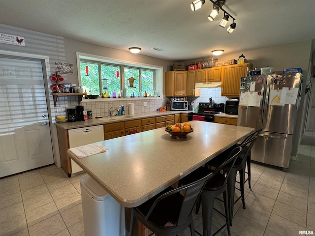 kitchen featuring a kitchen bar, decorative backsplash, rail lighting, and stainless steel appliances