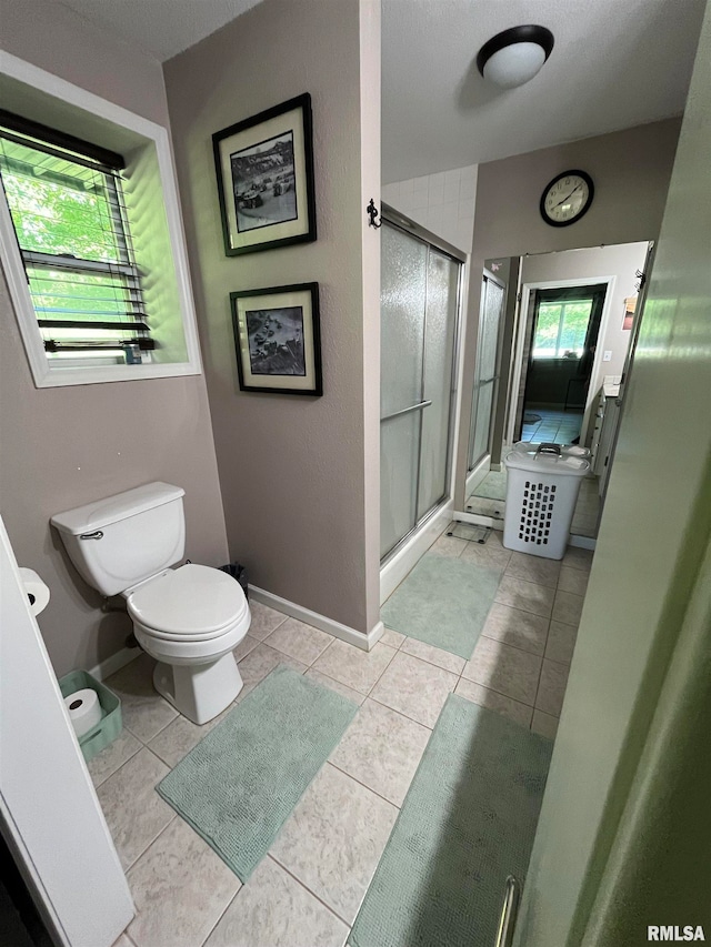 bathroom with toilet, tile patterned flooring, and walk in shower