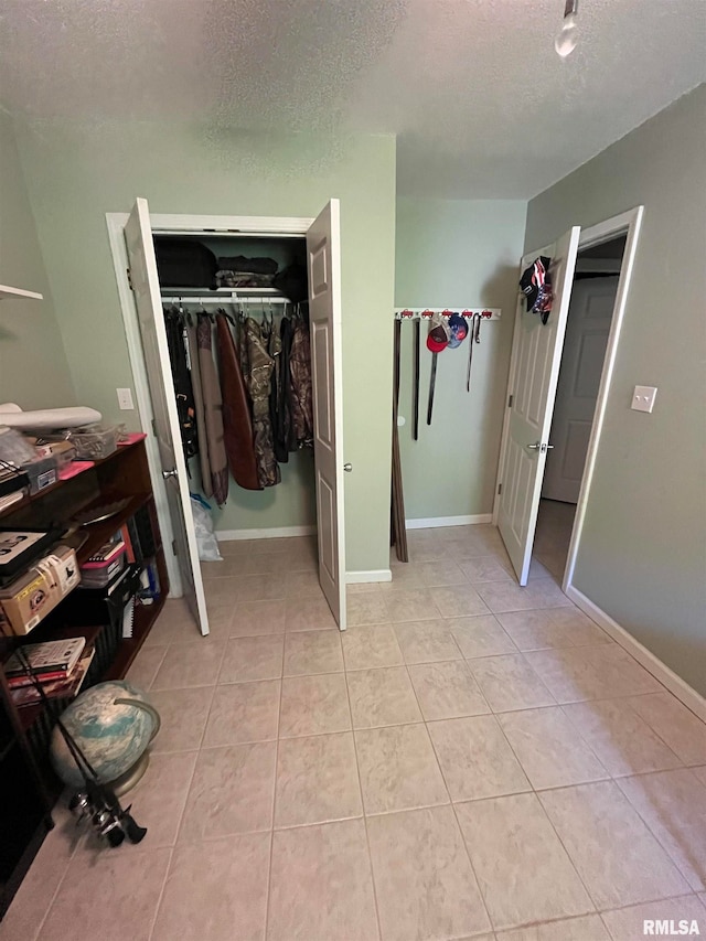 unfurnished bedroom featuring a textured ceiling, a closet, and light tile patterned floors