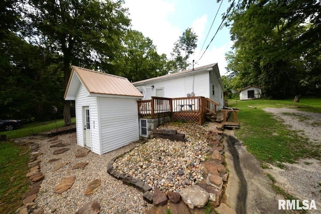 exterior space with metal roof, a storage shed, a yard, a deck, and an outbuilding