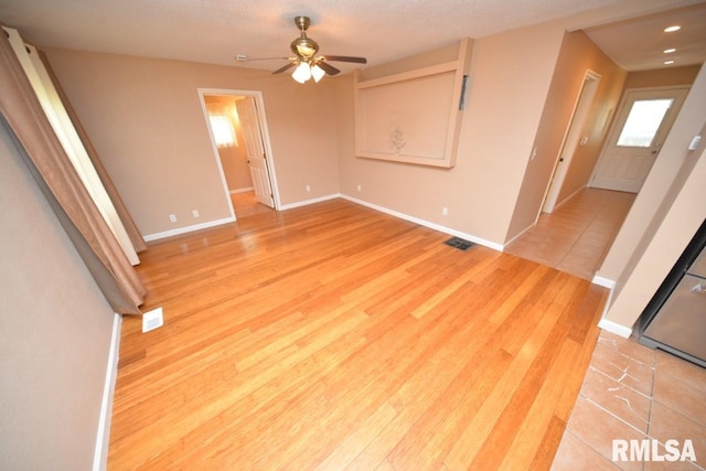 empty room with a textured ceiling, light hardwood / wood-style floors, and ceiling fan