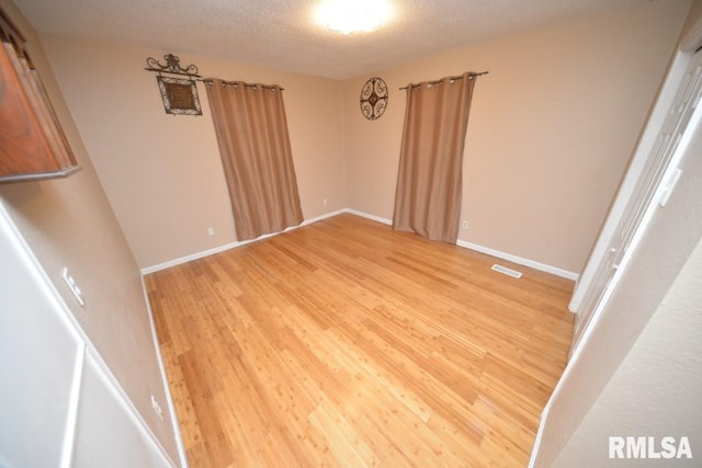 empty room with light hardwood / wood-style floors and a textured ceiling