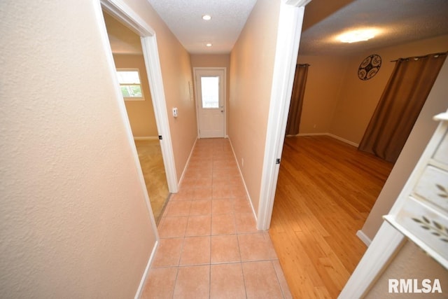 hall featuring a textured ceiling and light wood-type flooring