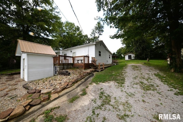 view of side of property featuring a deck and a storage shed