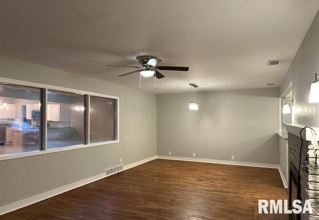 unfurnished living room with dark wood-type flooring, ceiling fan, and a fireplace