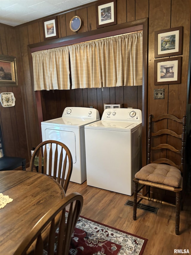 laundry room featuring washing machine and dryer, wood walls, and light hardwood / wood-style flooring