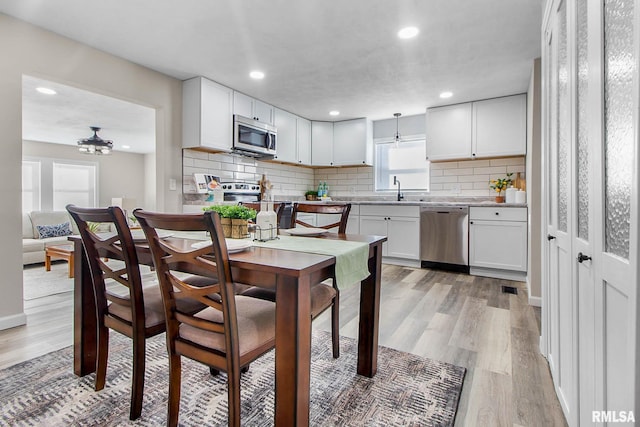 kitchen with white cabinetry, appliances with stainless steel finishes, and light hardwood / wood-style flooring