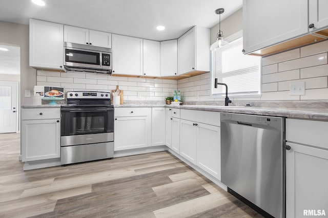 kitchen with white cabinetry, appliances with stainless steel finishes, and decorative light fixtures