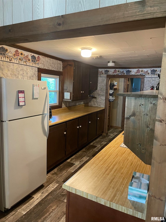 kitchen featuring beam ceiling, dark brown cabinets, wood-type flooring, and white refrigerator