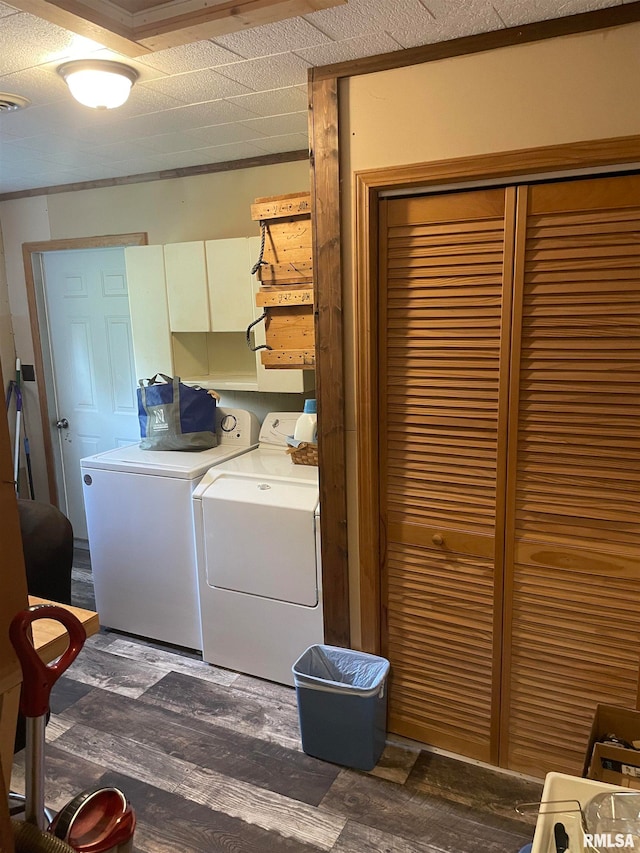 washroom with washing machine and dryer, cabinets, and wood-type flooring