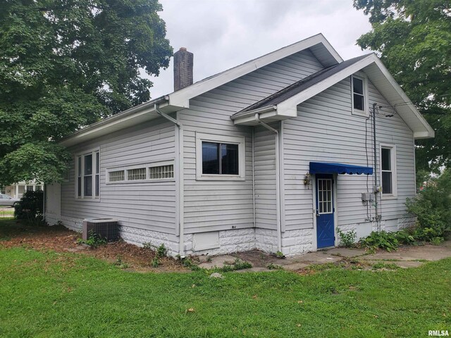 view of side of home with central AC and a lawn