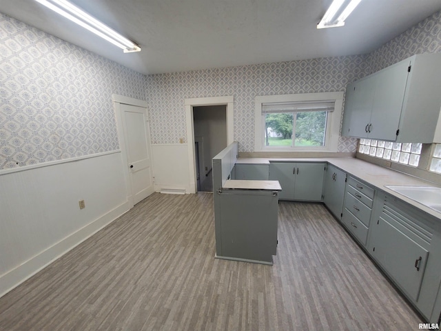 kitchen featuring sink, light hardwood / wood-style floors, a kitchen island, and gray cabinetry