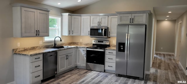 kitchen with white cabinets, lofted ceiling, sink, wood-type flooring, and stainless steel appliances