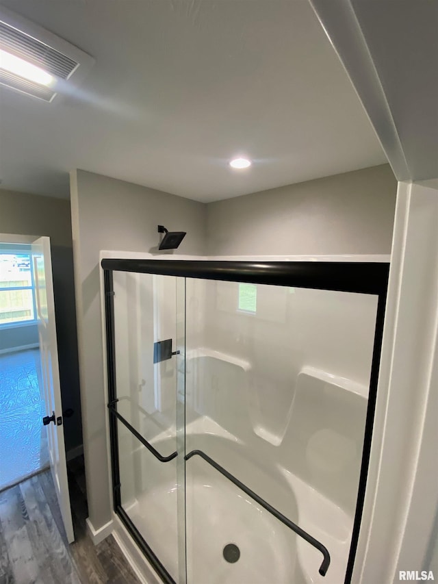 bathroom with hardwood / wood-style floors and a shower with shower door