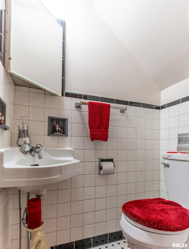 bathroom with lofted ceiling, decorative backsplash, toilet, tile walls, and tile patterned floors