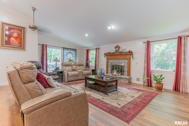 living room featuring a fireplace, lofted ceiling, light hardwood / wood-style floors, and crown molding