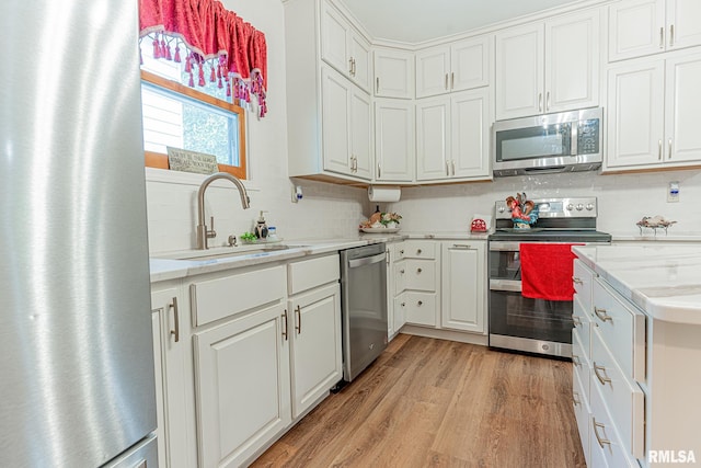 kitchen featuring white cabinets, stainless steel appliances, sink, and light hardwood / wood-style floors