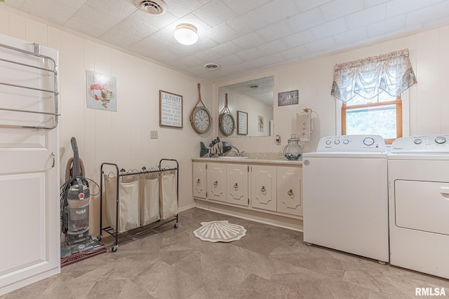 clothes washing area with cabinets, light carpet, wooden walls, separate washer and dryer, and sink