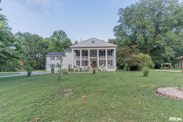 greek revival house featuring a front lawn and covered porch