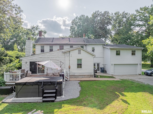 back of property featuring a yard, a garage, and a deck