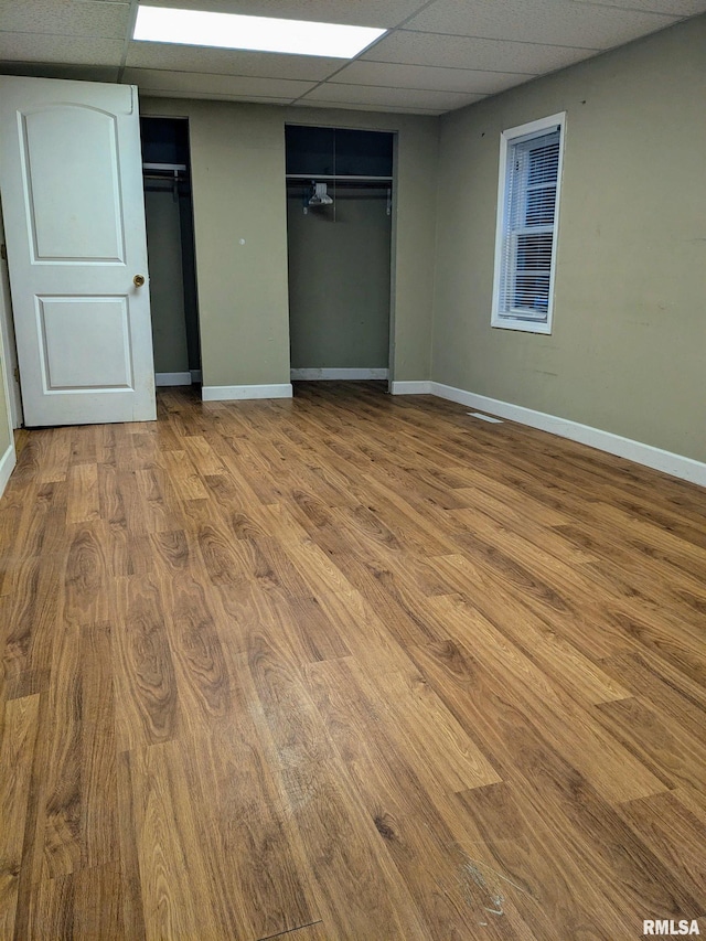 unfurnished bedroom with a paneled ceiling, hardwood / wood-style floors, and a closet