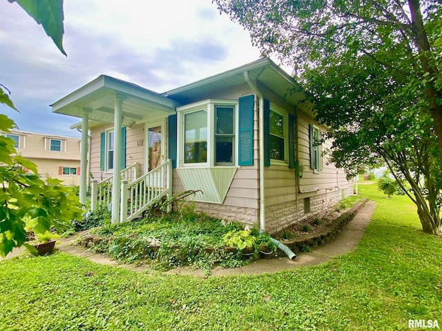 view of side of home with a yard and a porch