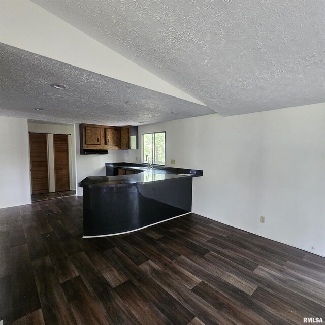 kitchen featuring a textured ceiling, dark wood-type flooring, and kitchen peninsula