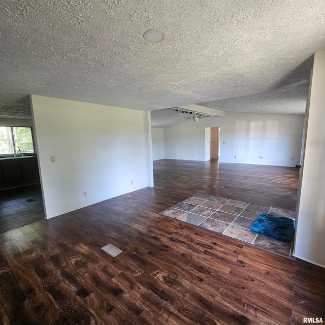 unfurnished living room featuring dark wood-type flooring and a textured ceiling