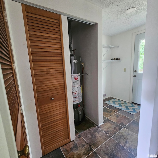 corridor with gas water heater and a textured ceiling