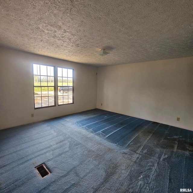 empty room with a textured ceiling and dark carpet