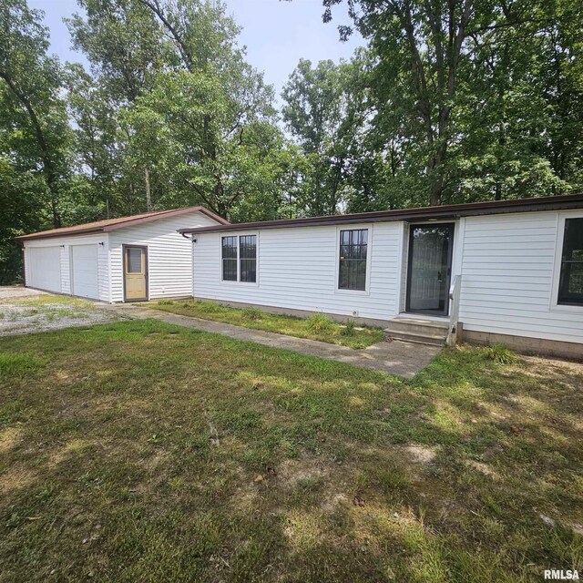 manufactured / mobile home featuring an outbuilding, a garage, and a front lawn