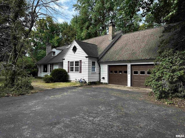 cape cod home featuring a garage