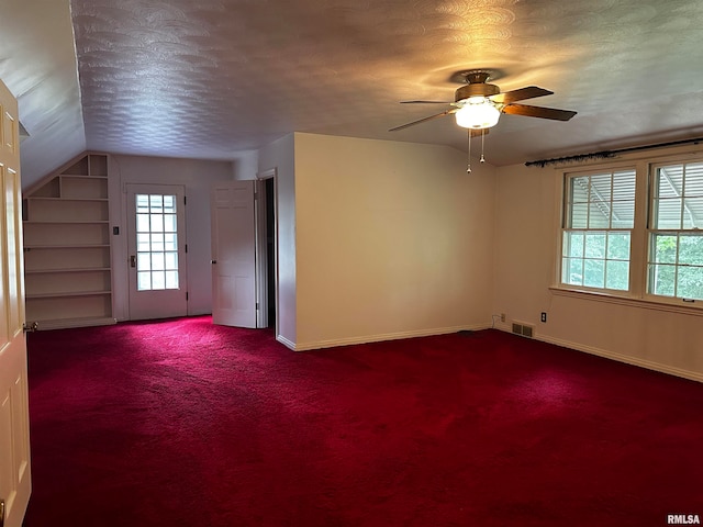 empty room featuring ceiling fan, a textured ceiling, lofted ceiling, and carpet floors