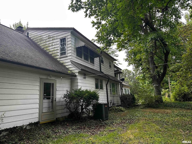 view of side of home with cooling unit and a lawn