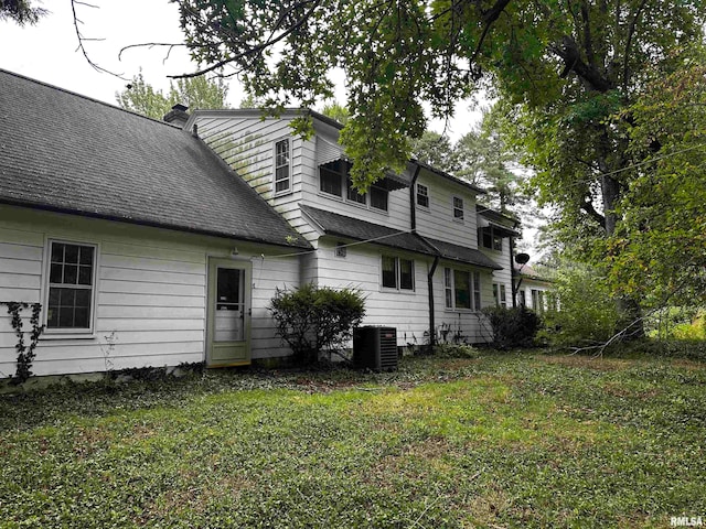 back of property with cooling unit and a lawn