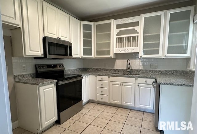 kitchen featuring appliances with stainless steel finishes, decorative backsplash, white cabinetry, sink, and light tile patterned flooring