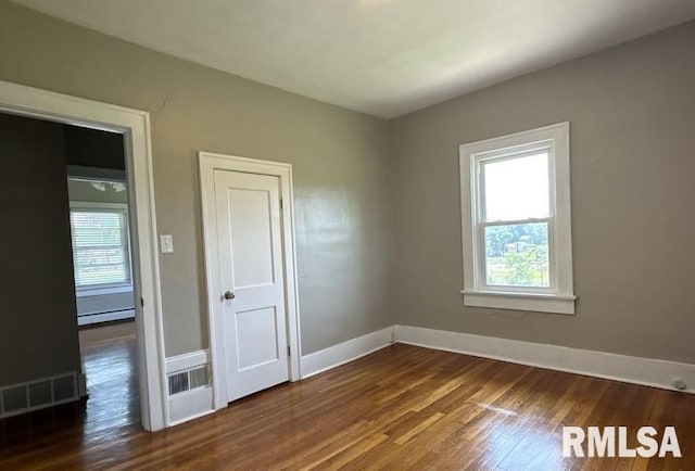 unfurnished bedroom featuring hardwood / wood-style floors and a baseboard radiator