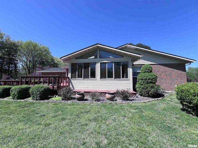 view of home's exterior featuring a deck, a lawn, and brick siding