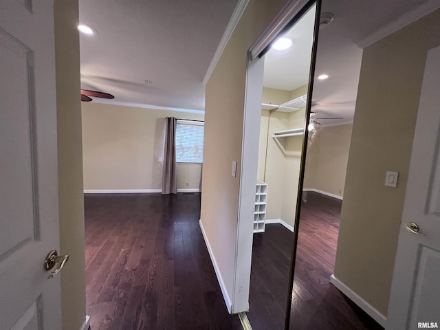 hall featuring baseboards, wood finished floors, and crown molding