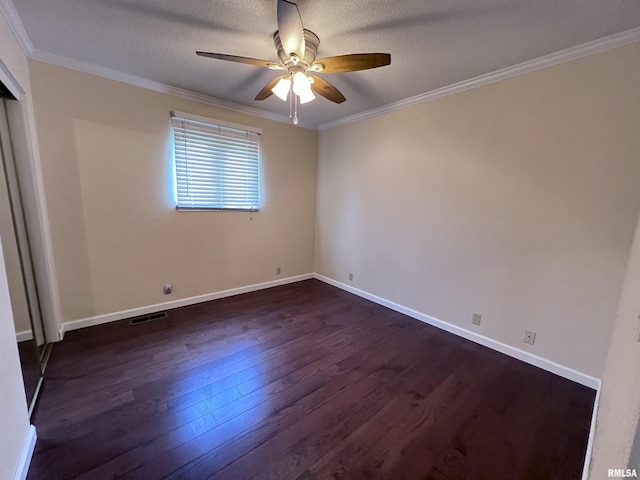 unfurnished room featuring baseboards, dark wood finished floors, visible vents, and crown molding