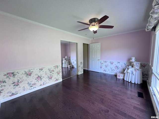 unfurnished room featuring ornamental molding, wood finished floors, visible vents, and wallpapered walls