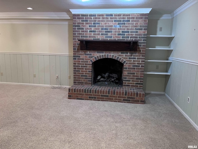 unfurnished living room with a brick fireplace, ornamental molding, carpet flooring, and a wainscoted wall