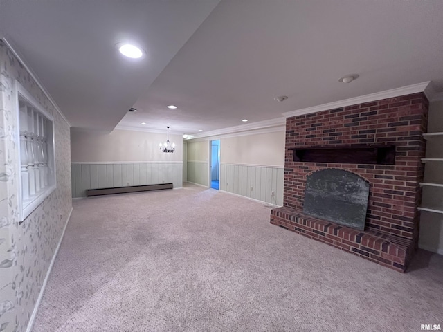 unfurnished living room with carpet floors, a wainscoted wall, crown molding, baseboard heating, and a brick fireplace