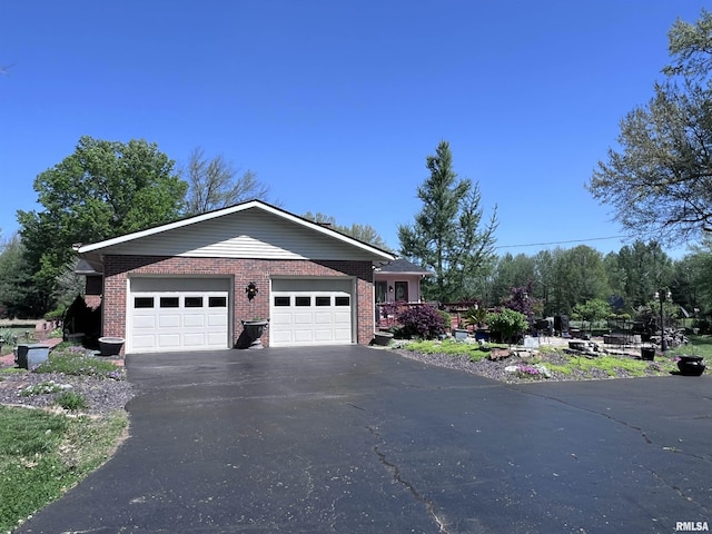 ranch-style house with a garage, brick siding, and aphalt driveway