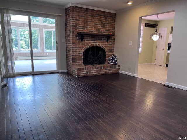 unfurnished living room featuring visible vents, baseboard heating, ornamental molding, a brick fireplace, and hardwood / wood-style flooring