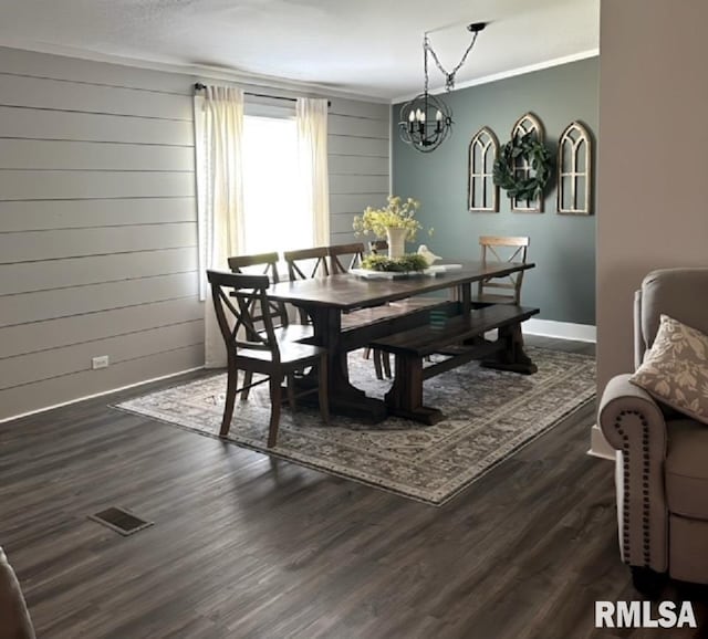 dining area featuring crown molding, dark wood-type flooring, and a chandelier