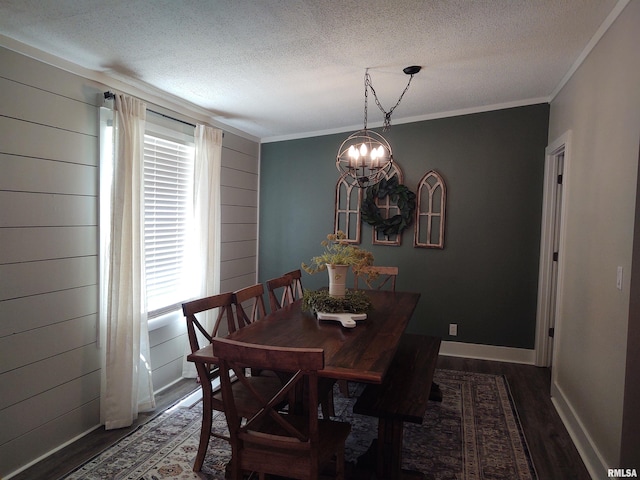 dining room with a textured ceiling, dark wood-type flooring, ornamental molding, and an inviting chandelier